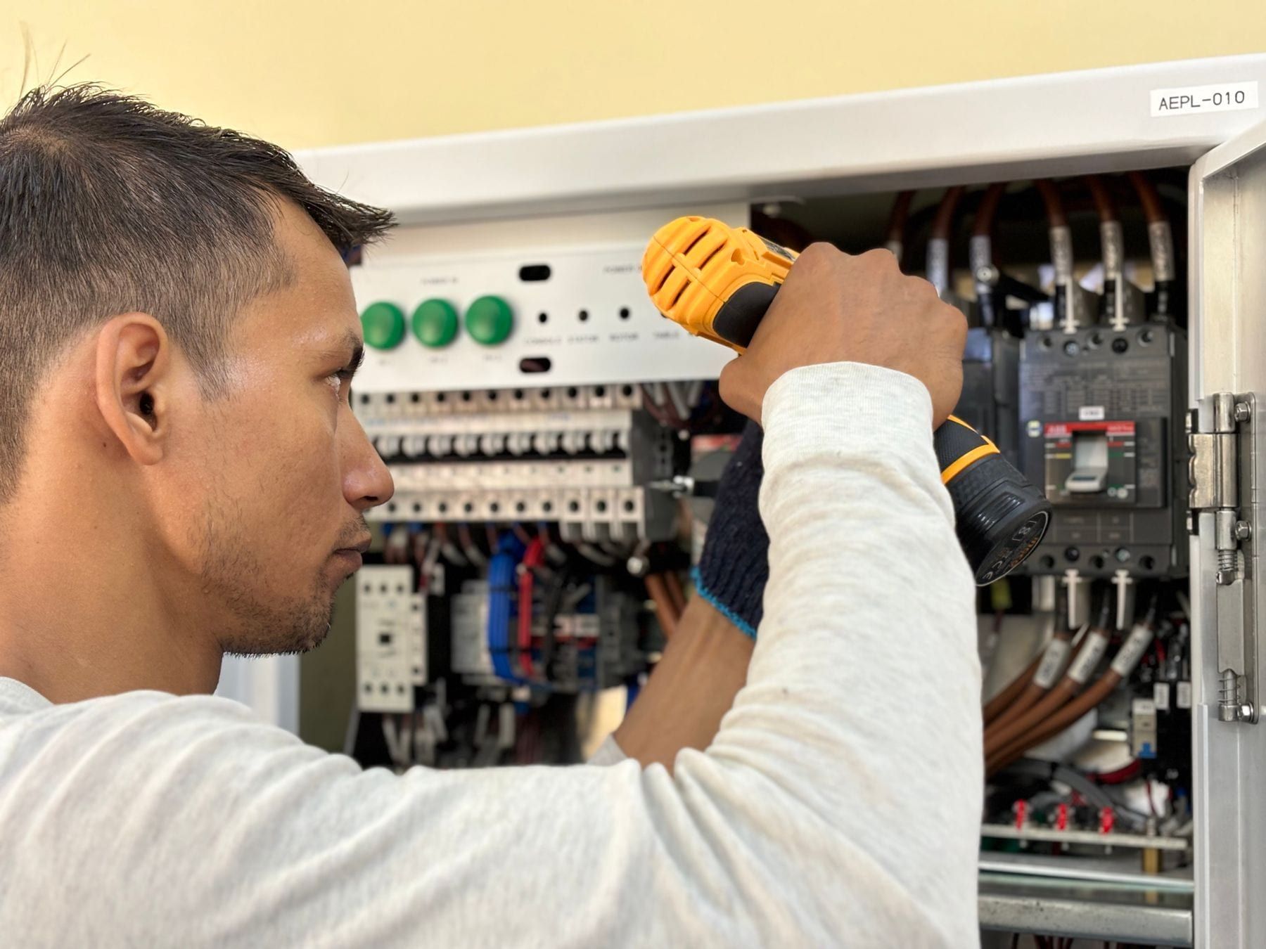 An electrician working inside an open residential breaker panel.